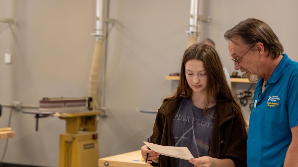 Construction technology instructor reviews a project with a student in a hands-on woodworking lab.